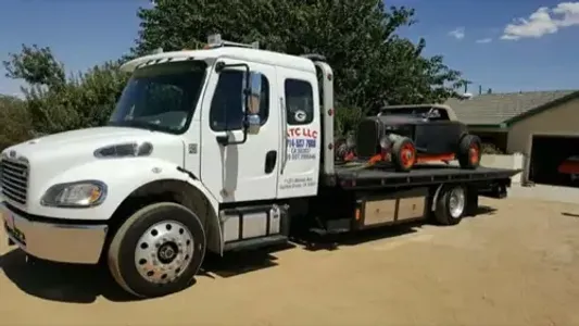 Flatbed truck carrying a hot rod